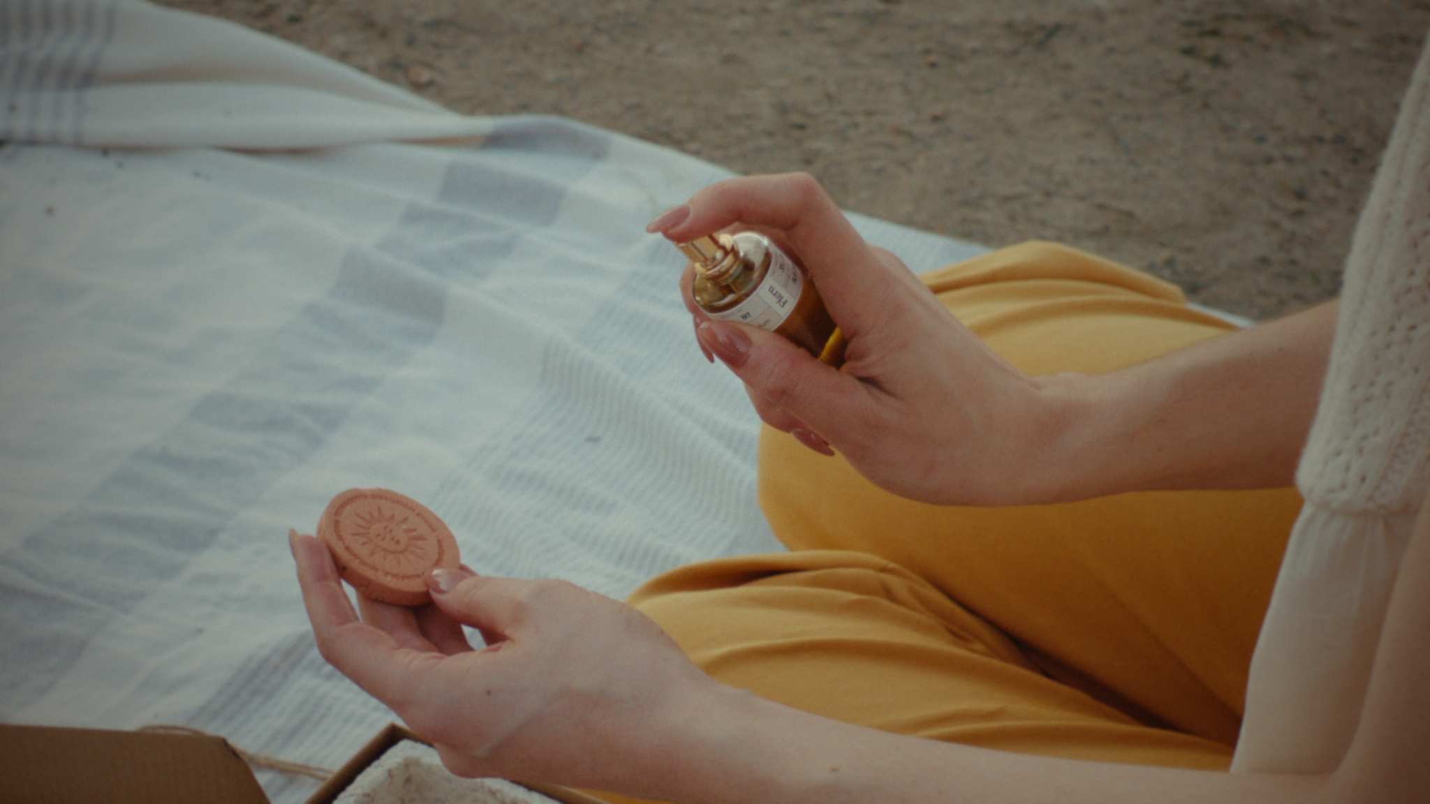 Hands holding a fragrance bottle and terracotta scent stone