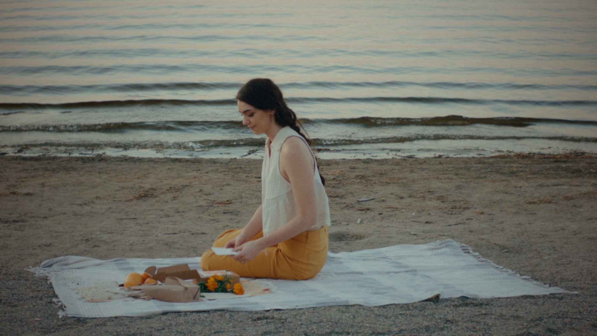 A woman seated at a quiet lakeside picnic at the end of summer