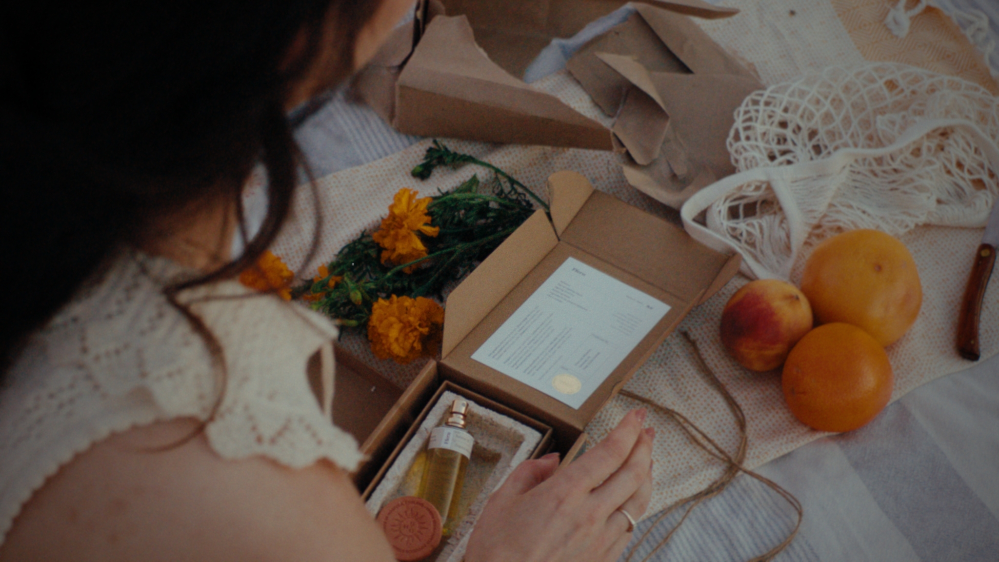 A fragrance parcel, summer fruit and marigolds arranged on a picnic blanket
