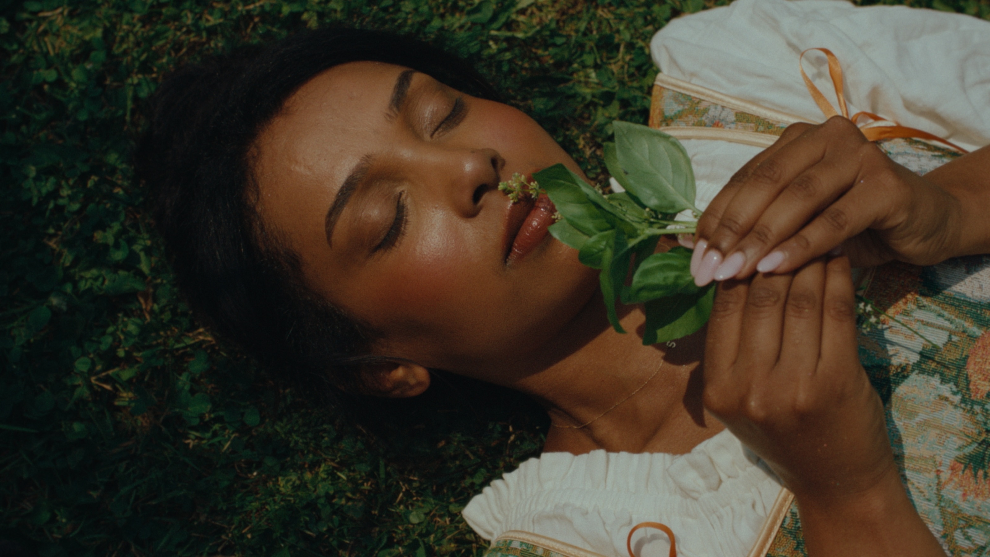 Sara lying in the grass with a sprig of basil