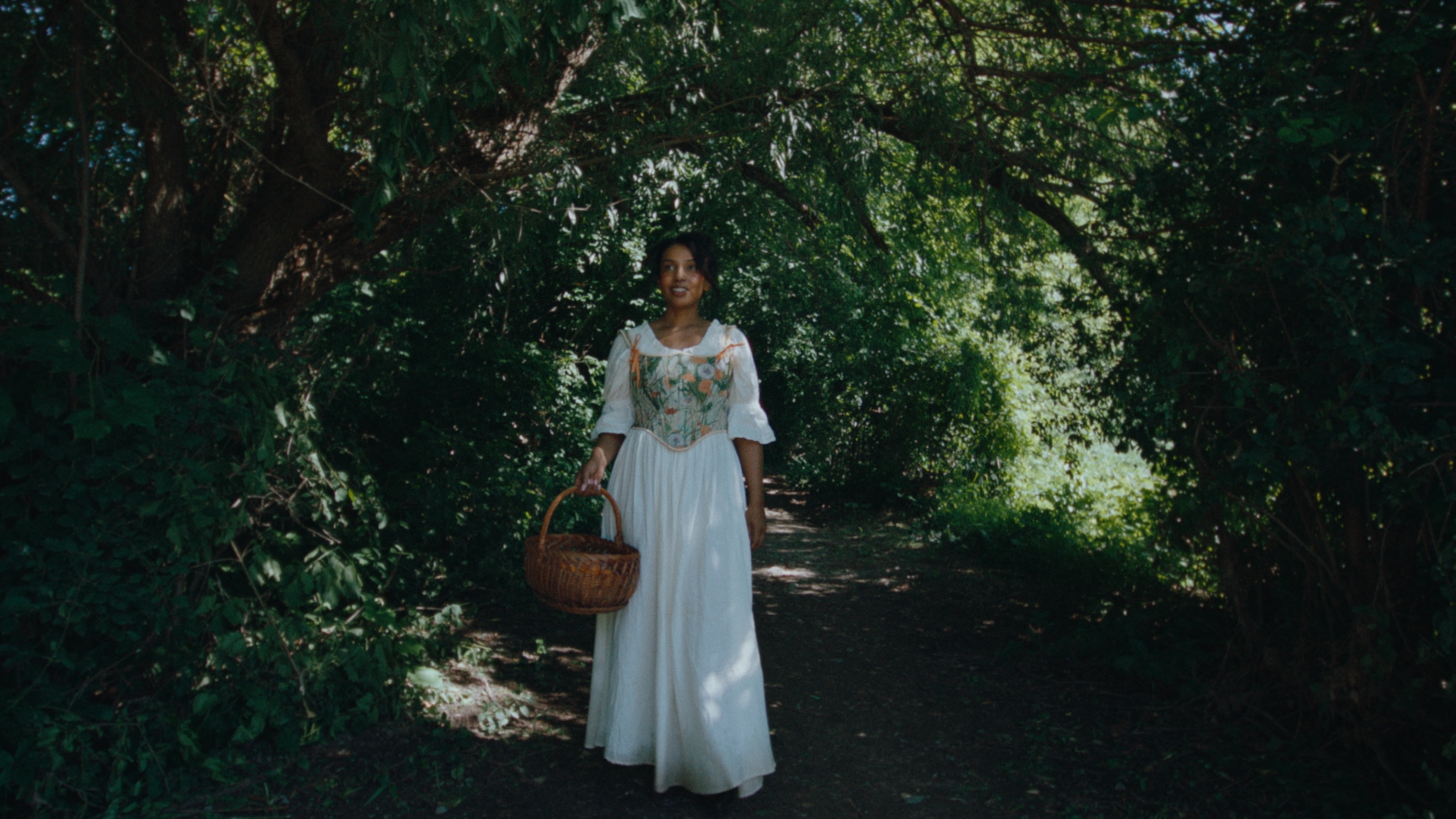 Sara standing at the threshold of a shaded garden path
