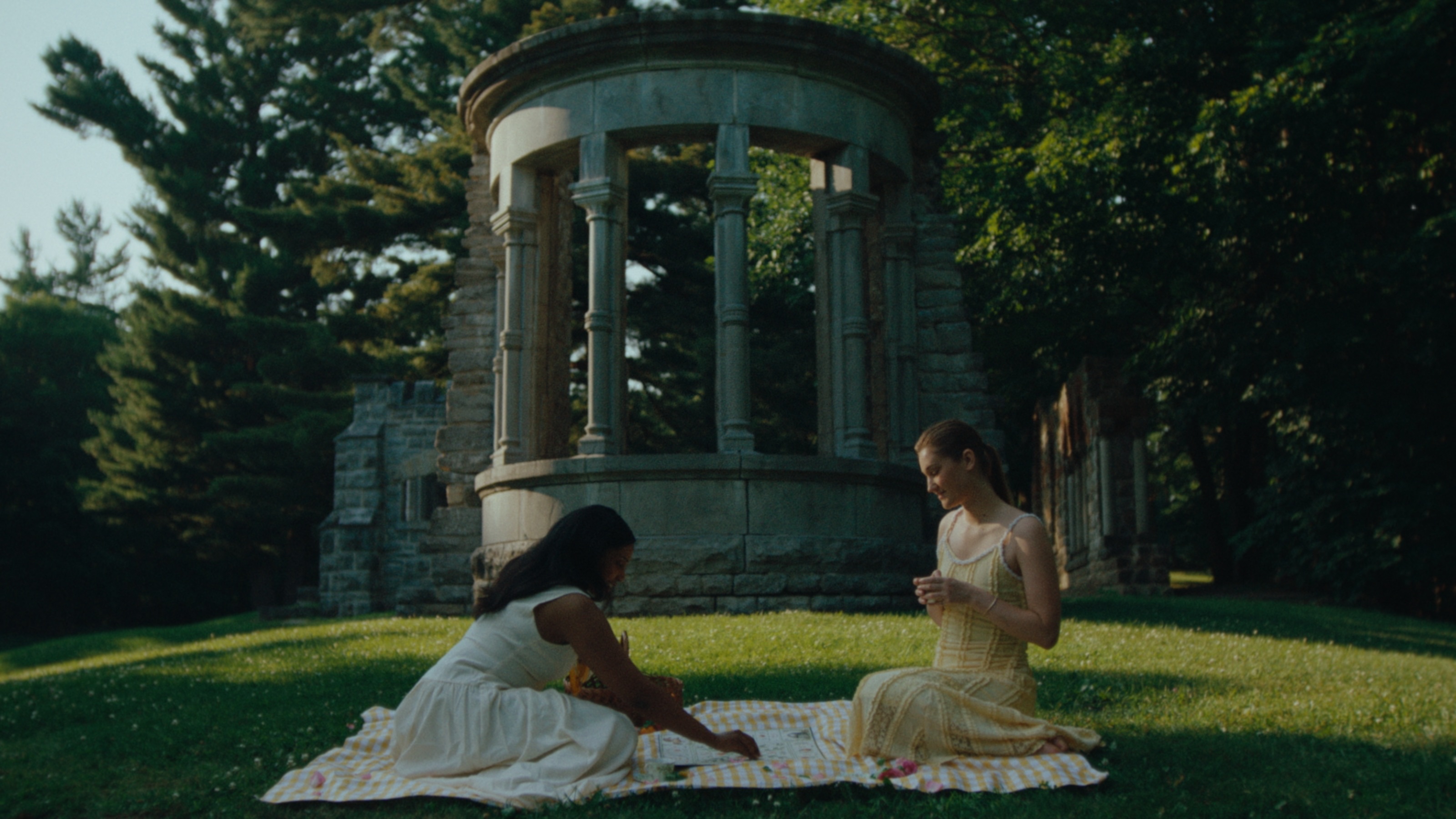 Two women playing an illustrated quest game at a summer picnic