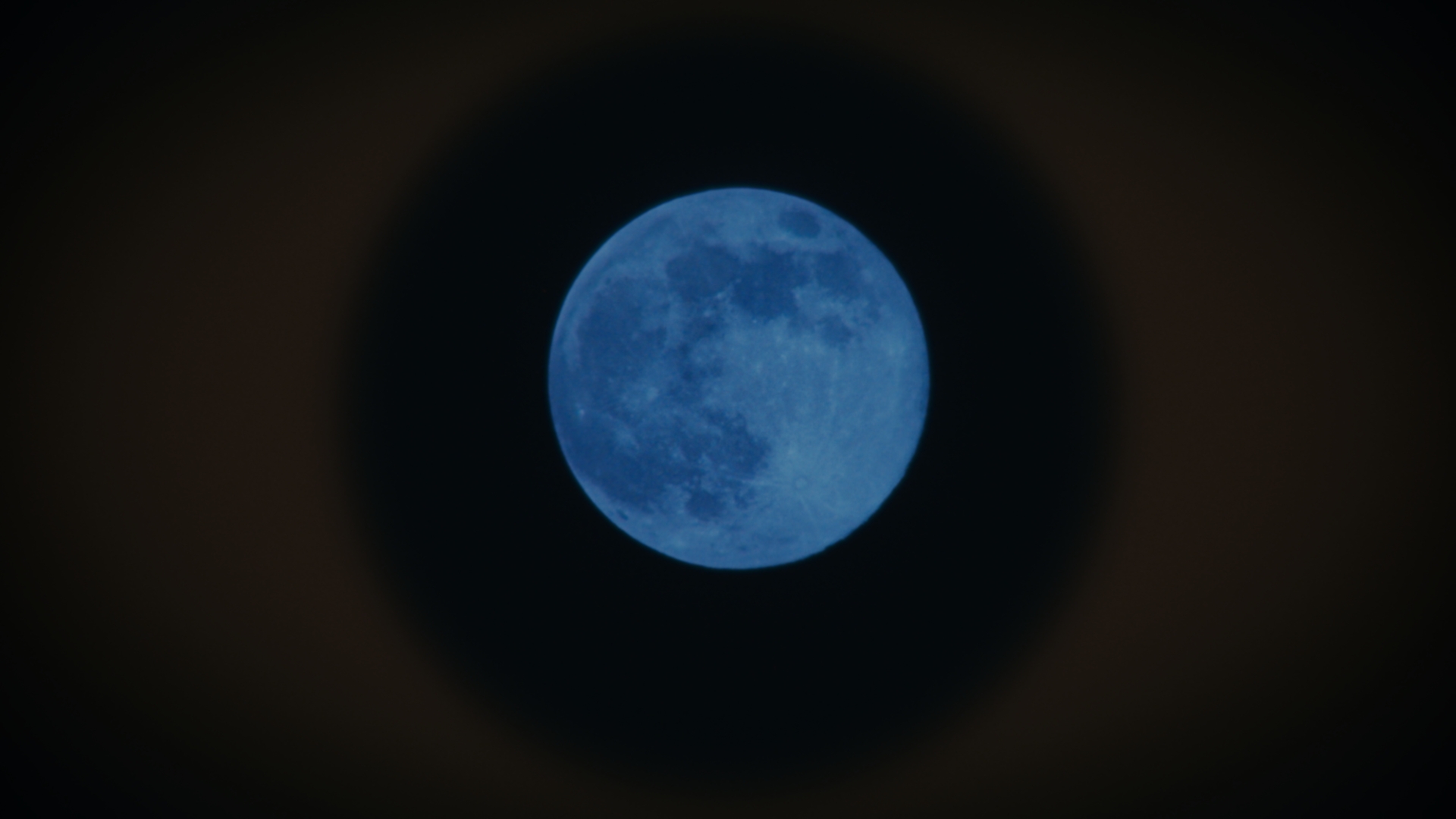 A blue moon suspended in the darkness
