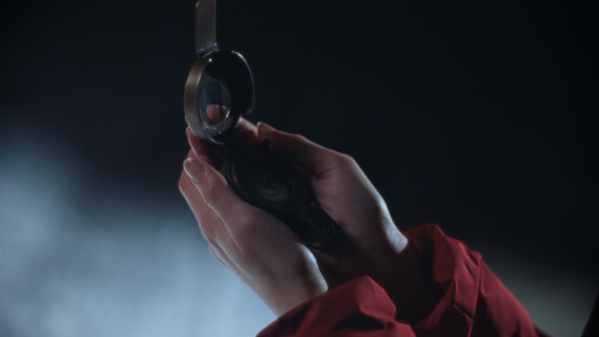 Hands holding an antique brass compass in moonlight