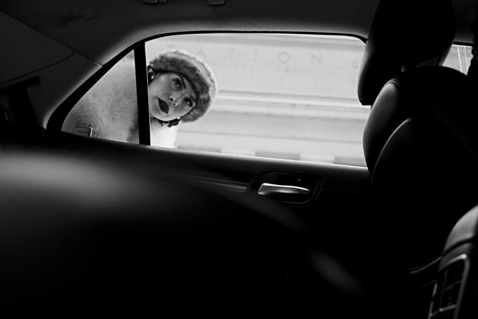 Gladys peering through the window of a waiting car