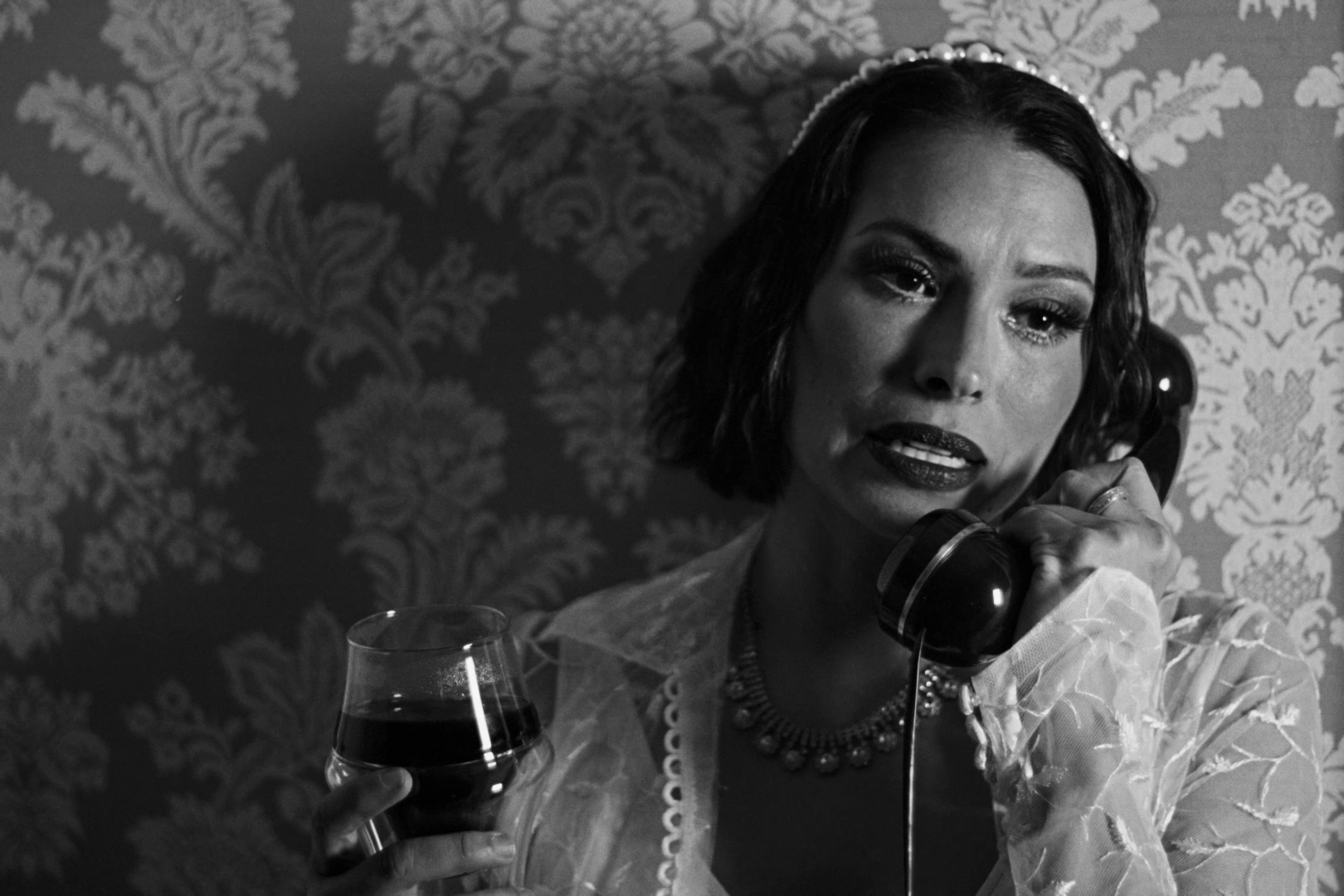 A close portrait of Gladys holding a rotary telephone and a glass