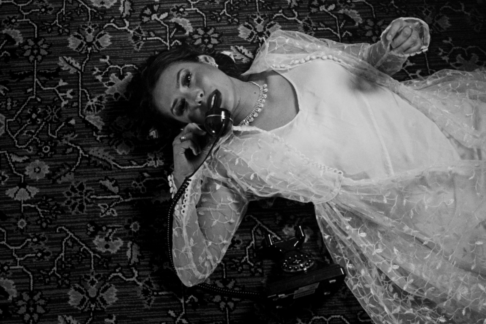 Gladys reclining on a patterned carpet beside a rotary telephone